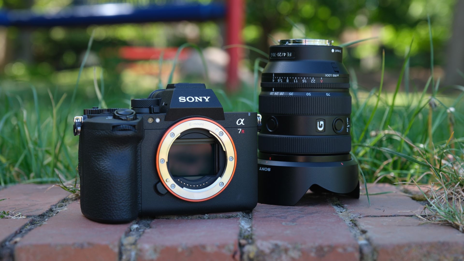 Sony A7R VI camera body beside a Sony FE20-70mm G lens in grass.